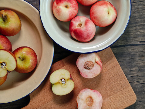 Red apple pink peach fruit whole sliced half seed tin plate chopping board wooded background