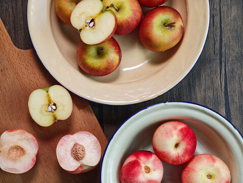 Red apple pink peach fruit whole sliced half seed tin plate chopping board wooded background
