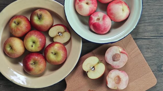 Red apple pink peach fruit whole sliced half seed tin plate chopping board wooded background