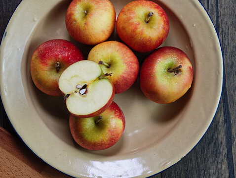 Red apple pink peach fruit whole sliced half seed tin plate chopping board wooded background