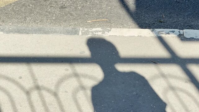 A hurried passenger walks past long shadows at a sunny bus stop in Simferopol, Crimea. The bright daylight brings a lively and hopeful feeling to the morning commute.