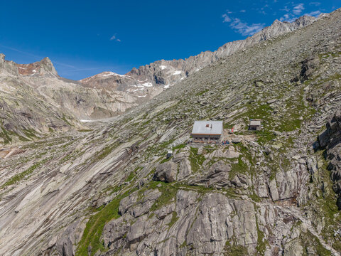 Guttannen, Canton of Bern, Switzerland - 07 July 2026: Aerial view of the Gelmerseehutte mountain refuge perched on a rocky slope surrounded by rugged alpine terrain and steep granite cliffs.