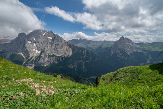 Alpine landscape with rugged dolomite peaks under a bright blue sky and fluffy white clouds, mountains