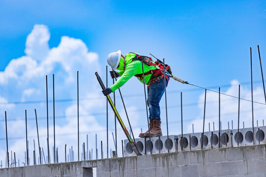 Side view of a construction worker using a pry bar to position precast hollow core concrete slabs at a building site