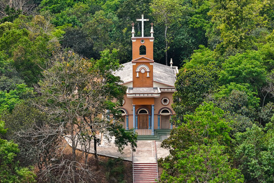 Sherpur, Mymensingh, Bangladesh - 05 April 2024: Aerial view of a church nestled in a dense forest, featuring a cross on its tower, brick architecture, and a stone staircase.