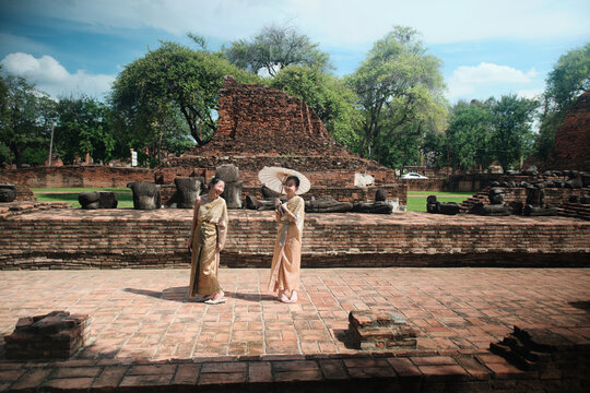 Asian family, mother and child dressed in Thai traditional outfit with cheerful smiles and looking at camera, holiday travel in Ayutthaya, Southeast Asia, ancient ruins heritage,  tourist destination.