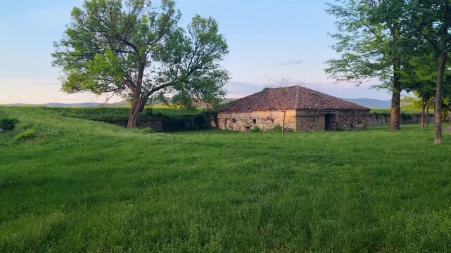 Evening view of a Ottoman Powder Magazine (Barutane) inside Ni&scaron; Fortress, Serbia, bathed in warm sunlight and surrounded by lush green grass, peaceful atmosphere at this historic landmark