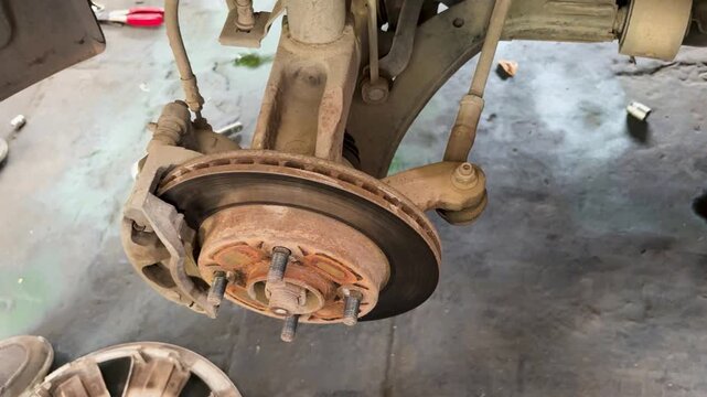 automotive technician checking front brake rotor and caliper in professional repair garage