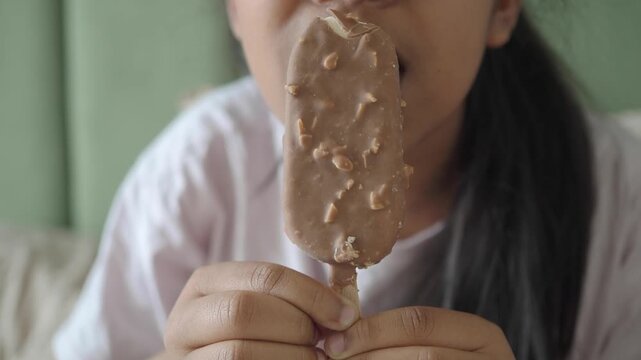 Holding a chocolate ice cream bar with nuts