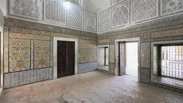 Historic interior with detailed Islamic tiles, carved plaster arches, and chandelier-lit dome in Zawiya of Sidi Sahib also known as the Mosque of the Barber in Kairouan. Tunisia.
