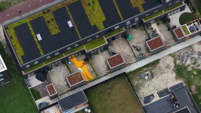 Top down aerial perspective of a contemporary residential area featuring homes with sedum green roofs and solar panels, showcasing sustainable and modern architectural design in a suburban setting