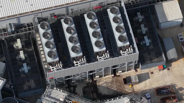 Aerial view of a large datacenter with its cooling system, featuring numerous fans on the roof maintaining the optimal temperature for servers processing big data and machine learning tasks