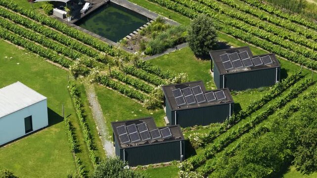 Aerial view of tiny houses in an eco village, showcasing self sufficient living, solar panels, green residential design and a sustainable community setting.