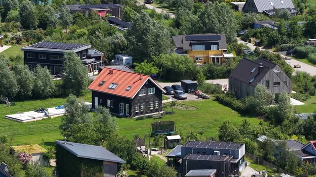 Aerial view of tiny houses in an eco village, showcasing self sufficient living, solar panels, green residential design and a sustainable community setting.