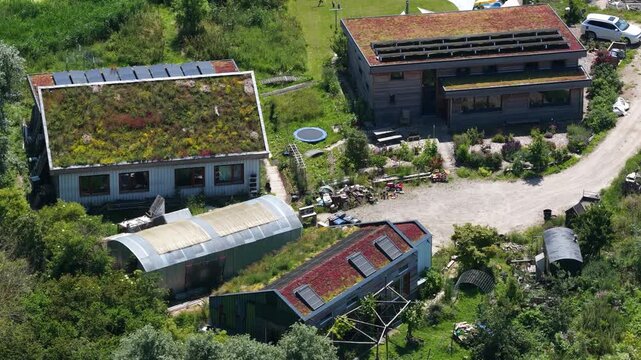 Aerial view of tiny houses in an eco village, showcasing self sufficient living, solar panels, green residential design and a sustainable community setting.