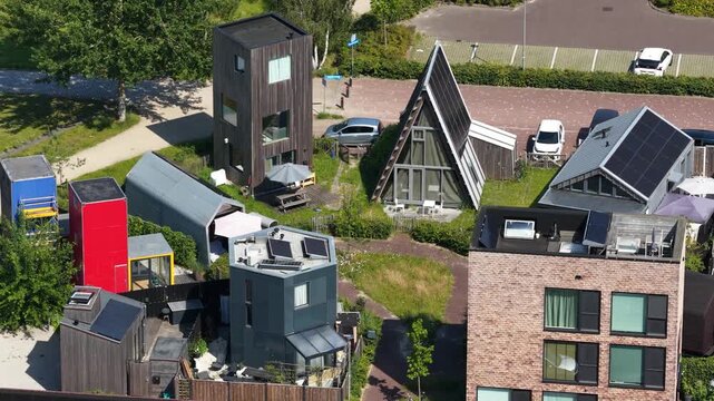 Aerial view of tiny houses in an eco village, showcasing self sufficient living, solar panels, green residential design and a sustainable community setting.