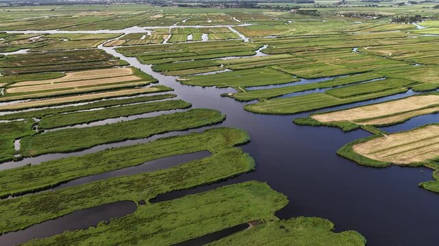 Stunning aerial perspective showing the unique polder landscape of the netherlands, with lush green fields and agricultural plots intricately divided by a network of canals and waterways