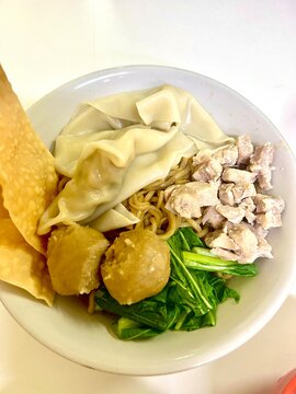 Close up of chicken noodle with steamed dumplings, cracker, meat, meatball and steamed green vegetable. Called Mie Ayam In Indonesia