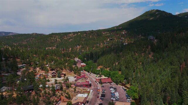 Downtown Evergreen Colorado main street business buildings cars aerial drone view Front Range Bear Mountain Rocky Mountains small town summer spring sunny cloudy morning forward motion