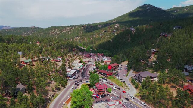 Downtown Evergreen small mountain town aerial drone view main street business buildings Colorado cars Front Range Rocky Mountains summer spring sunny cloudy morning forward pan up motion