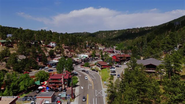 Cityscape downtown Evergreen small mountain town aerial drone view main street business buildings Colorado cars Front Range Rocky Mountains summer spring sunny cloudy morning upwards motion