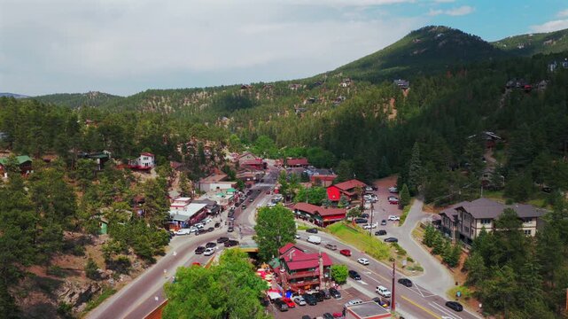 Downtown Evergreen small mountain town aerial drone view main street business buildings Colorado cars Front Range Rocky Mountains summer spring sunny cloudy morning backwards up pan up motion