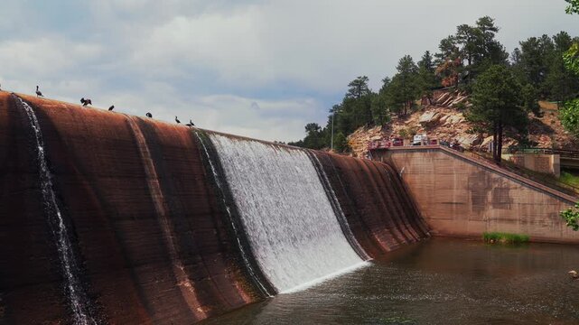 Evergreen Lake dam structure birds resting nature landscape downtown Evergreen Colorado morning sunny clouds blue sky spring summertime small Rocky Mountain town walking hike stair set trails pan left