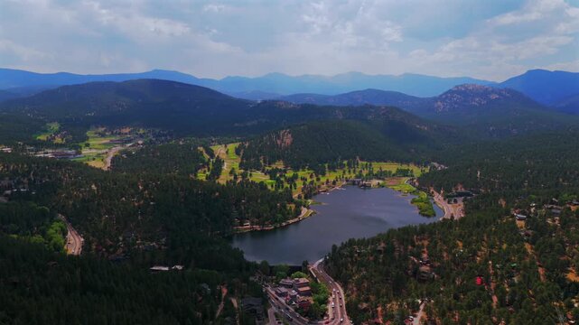 Spring summer aerial drone downtown Evergreen Colorado's Evergreen Lake nature landscape Snow-covered Mt Blue Sky Evans 14er Front Range Rocky Mountains foothills sunny clouds backwards upwards