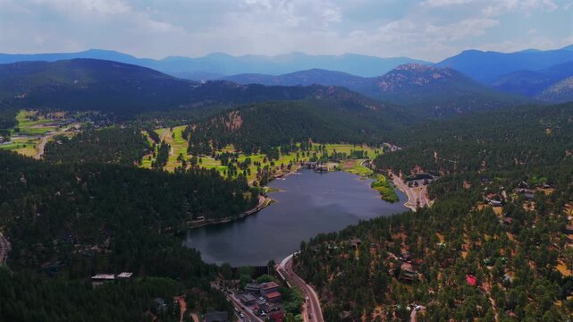 Spring summer aerial drone view of downtown Evergreen Colorado's Evergreen Lake nature landscape Snow-covered Mt Blue Sky Evans 14er Front Range Rocky Mountains foothills Three Sisters Park pan left
