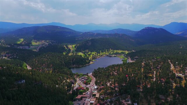 Spring summer aerial drone downtown Evergreen Colorado's Evergreen Lake nature landscape Snow-covered Mt Blue Sky Evans 14er Front Range Rocky Mountains foothills sunny road cars clouds forward pan up