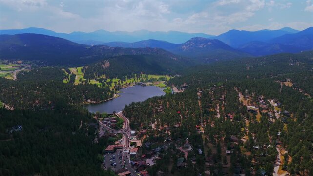 Spring summer aerial drone traffic cars downtown Evergreen Colorado's Evergreen Lake nature landscape Snow-covered Mt Blue Sky Evans 14er Front Range Rocky Mountains foothills sunny clouds pan left