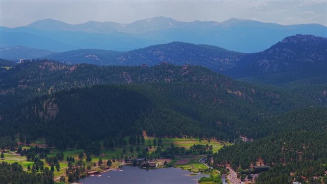 Summertime aerial drone view Evergreen Colorado's Evergreen Lake House landscape Snow-covered Mt Blue Sky Front Range Rocky Mountains foothills Denver Golf Course haze sky sunny clouds circle left