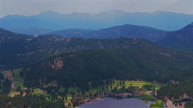 Summertime aerial drone view Evergreen Colorado's Evergreen Lake House Mt Blue Sky Front Range Rocky Mountains foothills landscape Snow-covered Denver Golf Course haze sky sunny clouds circle right