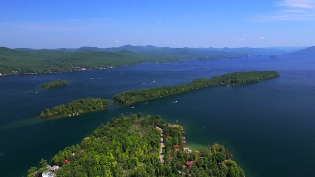 Boating Lake George Long Canoe Speaker Heck Island aerial drone Up State New York Town of Lake George homes landscape harbor view Assembly Point spring summer sunny morning blue sky forward pan up