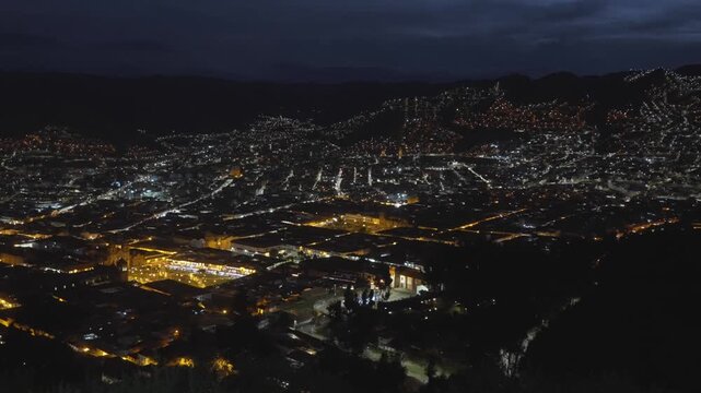 Cusco nighttime city street lights dusk Plaza de Armas main square city of Cuzco Peru cityscape landscape rainy season Peruvian neighborhood buildings on mountainside Anta Province Andes pan left