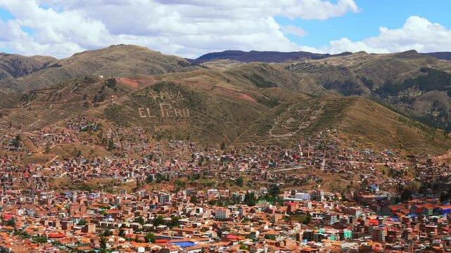 Cusco city of Cuzco Peru cityscape landscape rainy season sunny afternoon clouds blue sky Peruvian Andes neighborhood buildings on mountainside Anta Province Plaza de Armas main square pan left motion