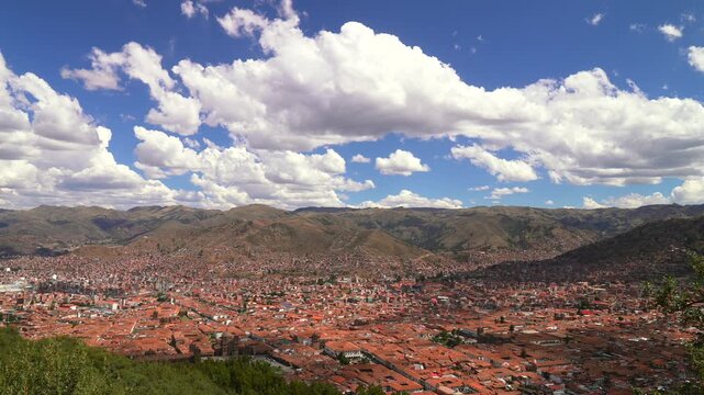 Cusco Saqsaywaman Inca city of Cuzco Peru cityscape landscape rainy season sunny afternoon clouds blue sky Peruvian Andes neighborhood buildings on mountainside Anta Province Plaza de Armas pan left
