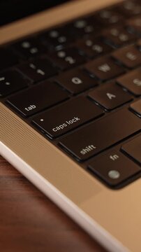 Finger Pressing Caps Lock Button on Laptop Keyboard in Warm Lighted Room.