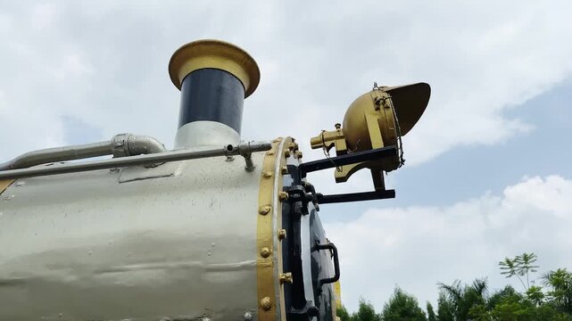 Orbiting close up view of a restored vintage steam locomotive highlighting the smokestack and front headlamp