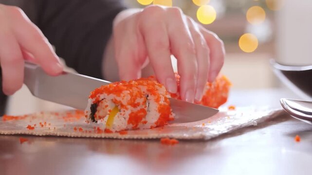 Chef slicing tobiko caviar california sushi roll with sharp knife close up 4K