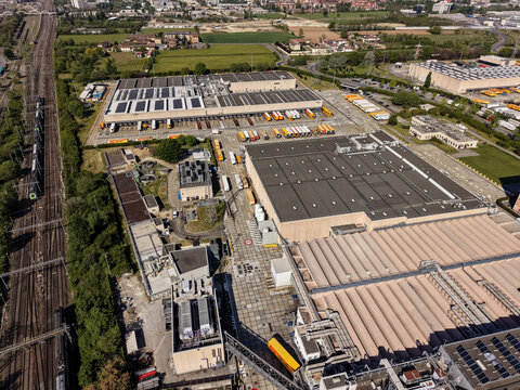 Pioltello, Lombardy, Italy - 18 May 2026: Aerial view of the Esselunga distribution center, featuring large warehouses, loading docks with trucks, and adjacent railway tracks.