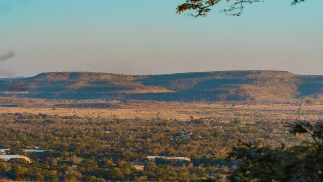 Kafue, Lusaka Province, Zambia - 19 July 2026: Aerial view of the Kafue landscape featuring rolling hills, dry savanna vegetation, and scattered buildings under a clear sky.