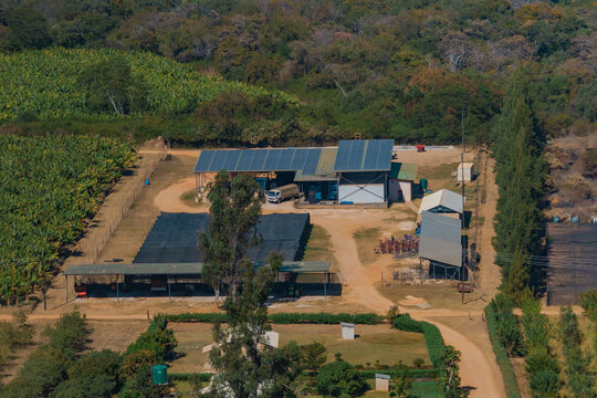 Kafue, Lusaka Province, Zambia - 19 July 2026: Aerial view of an agricultural facility with solar panels, surrounded by banana plantations, dirt roads, and dense woodland.