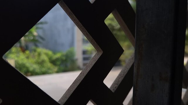 Close-Up of Dark Diamond Pattern Metal Fence with Blurred Outdoor Background