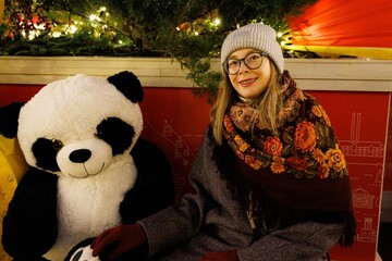 Cozy winter evening with a giant panda and a smiling woman in a festive setting © AlexKriv