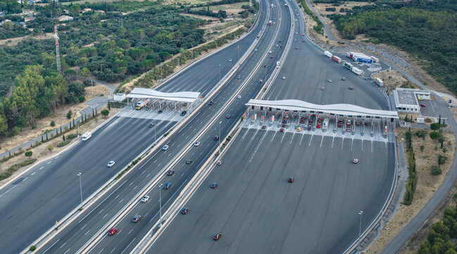 Baillargues, France - 18 July 2026: Aerial view of a highway toll plaza with flowing traffic, sweeping motorway lanes, and a wave-shaped roof showcasing modern transportation infrastructure.