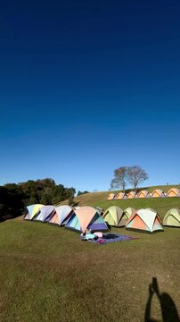 Panoramic view of colorful camping tents on a grassy hill at Doi Samer Dao in Sri Nan National Park, Nan, Thailand.