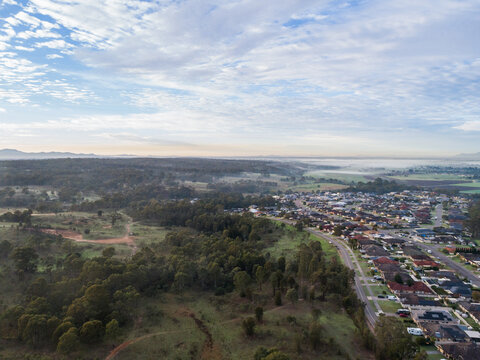 Dawn sky over edge of town where development of homes along streets meets bushland