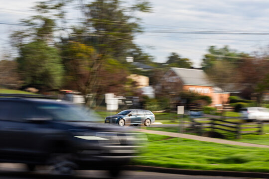 panning motion capture of car traveling down road on morning commute