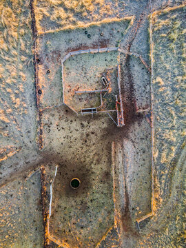 Looking down a dry farm stockyard with fences gates and water tank